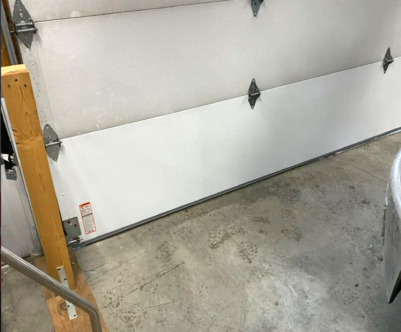 Close-up of a technician repairing a garage door panel with tools, showcasing the garage door panel repair process.