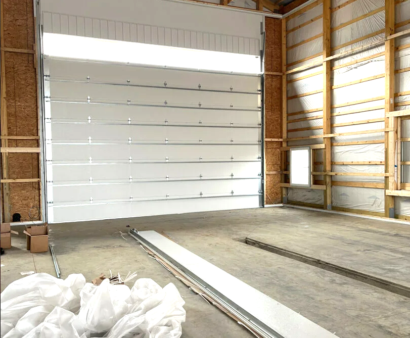 Technicians performing a garage door section replacement at a residential property in Westerville, showcasing tools and equipment in the background.