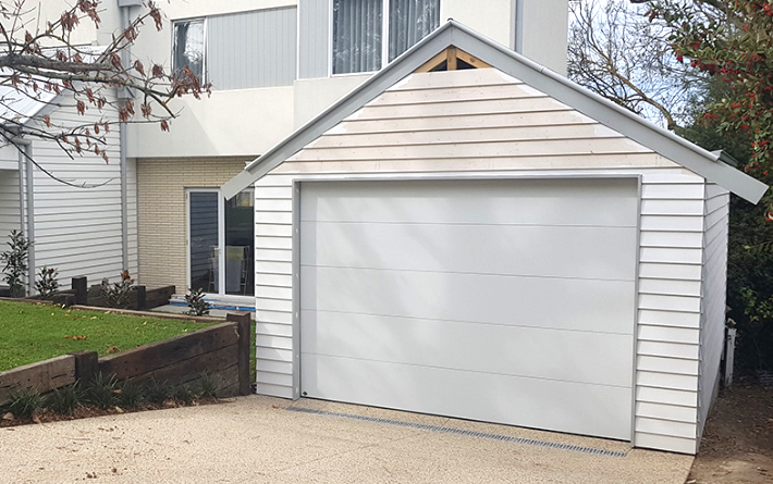 Technician repairing a garage door in a local residential area, showcasing Westerville Garage Door Repair's professional local garage door repair services, with recognizable neighborhood landmarks in the background